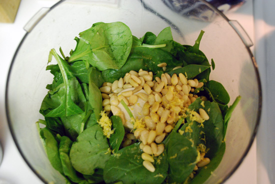 Place spinach, lemon juice, lemon peel and pine nuts in food processor.