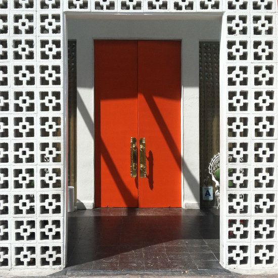 The tangerine doors, framed by chain-link-detailed walls, give guests a hint of the midcentury-themed decor that awaits.
The tangerine doors, framed by chain-link-detailed walls, give guests a hint of the midcentury-themed decor that awaits.