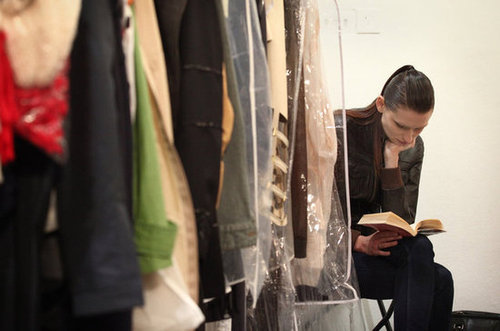 Hidden by a rack of clothing, this model read ahead of The Royal College of Art Fashion Show in London.
Hidden by a rack of clothing, this model read ahead of The Royal College of Art Fashion Show in London.