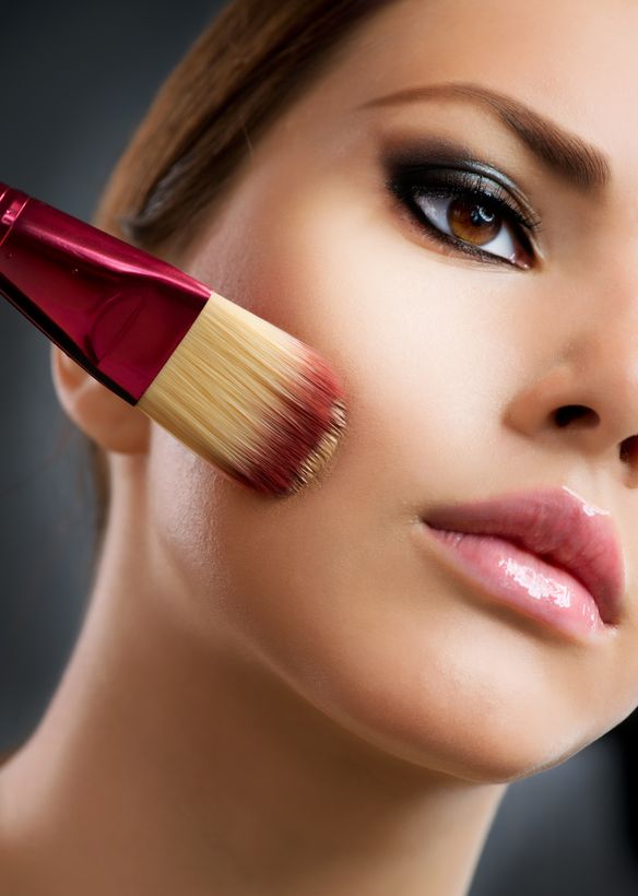 Beautiful woman using makeup brush