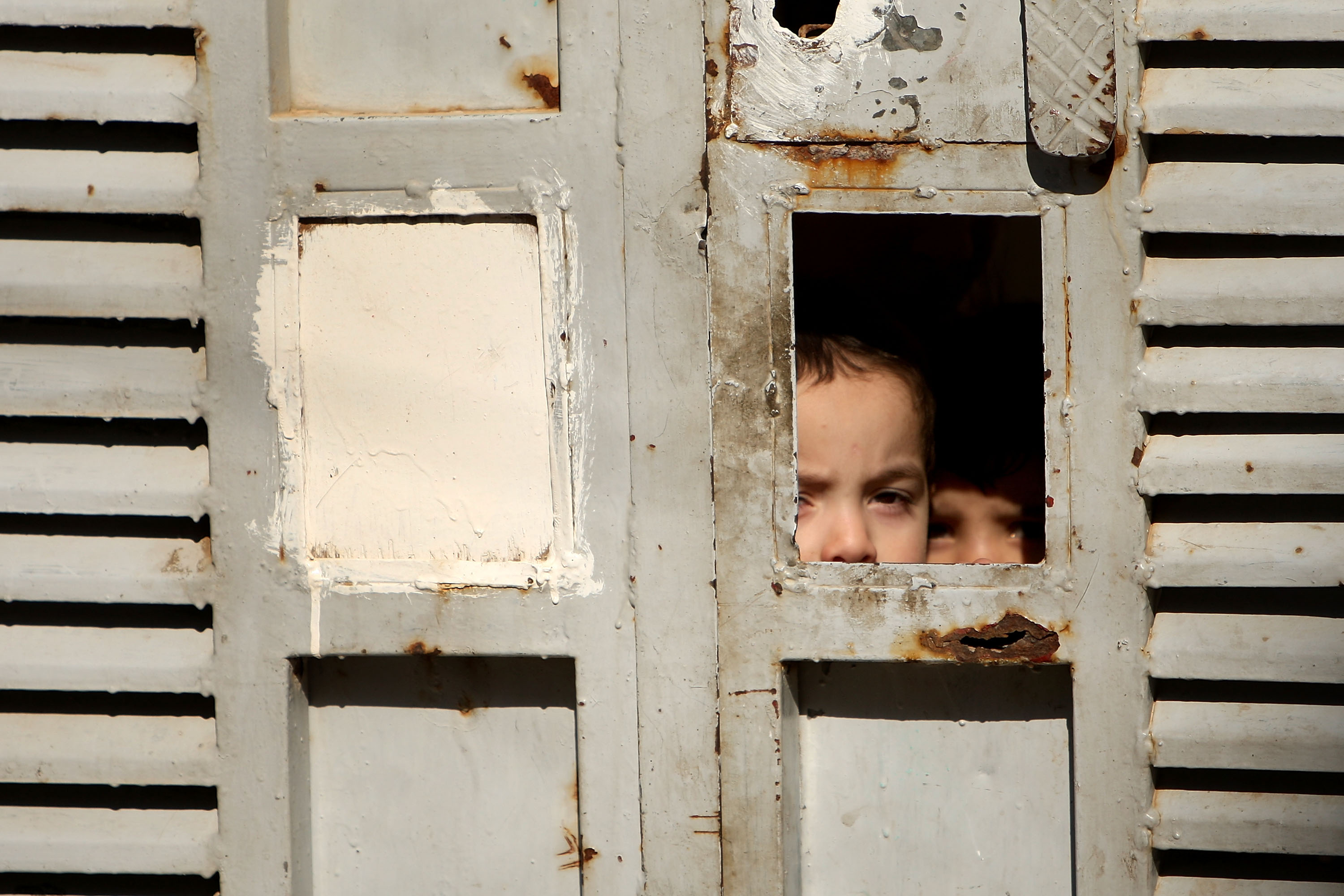 Children look out from a gate in Baghdad's Doura neighborhood March 7, 2008. Children look out from a gate in Baghdad's Doura neighborhood March 7, 2008.