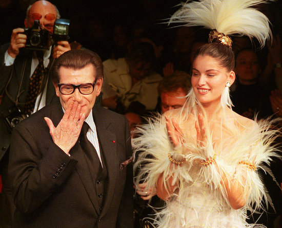 2000: Yves Saint Laurent blows a kiss at the end of his Spring 2000 couture presentation, with bride Laetitia Casta standing by.